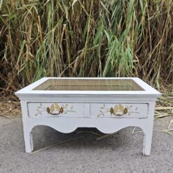 Shabby chic coffee table with glass top, decorative details and aged white finish.