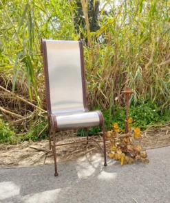 Sillón metálico con respaldo plateado y estructura de hierro forjado.