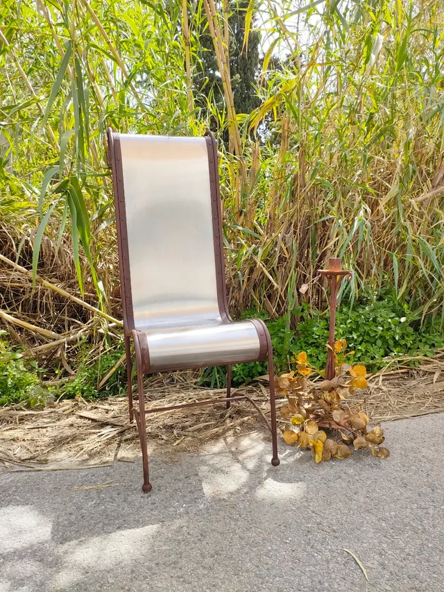 sillón metálico 1 Sillón metálico con respaldo plateado y estructura de hierro forjado.