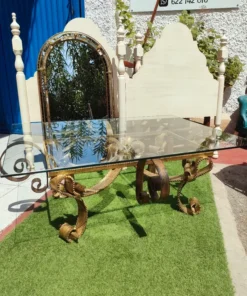 Mesa de hierro dorado con tapa de cristal.