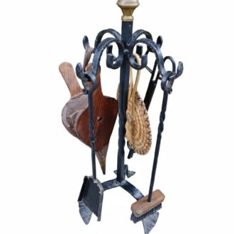 Set completo de accesorios para chimenea: soporte de forja, herramientas clásicas, fuelle de madera y cepillo trenzado. Funcionalidad tradicional con estética artesanal.